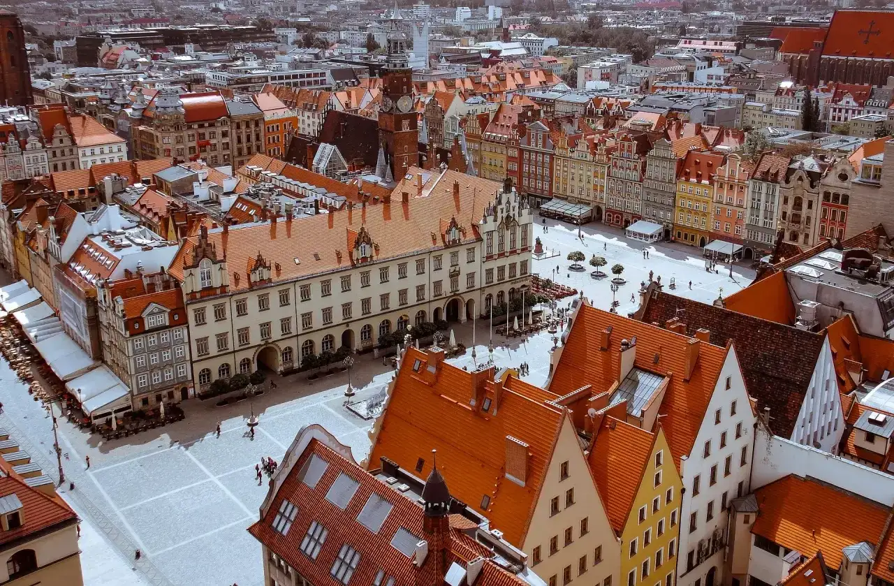 Widok z góry na Rynek we Wrocławiu z kolorowymi kamienicami i wieżą zegarową.